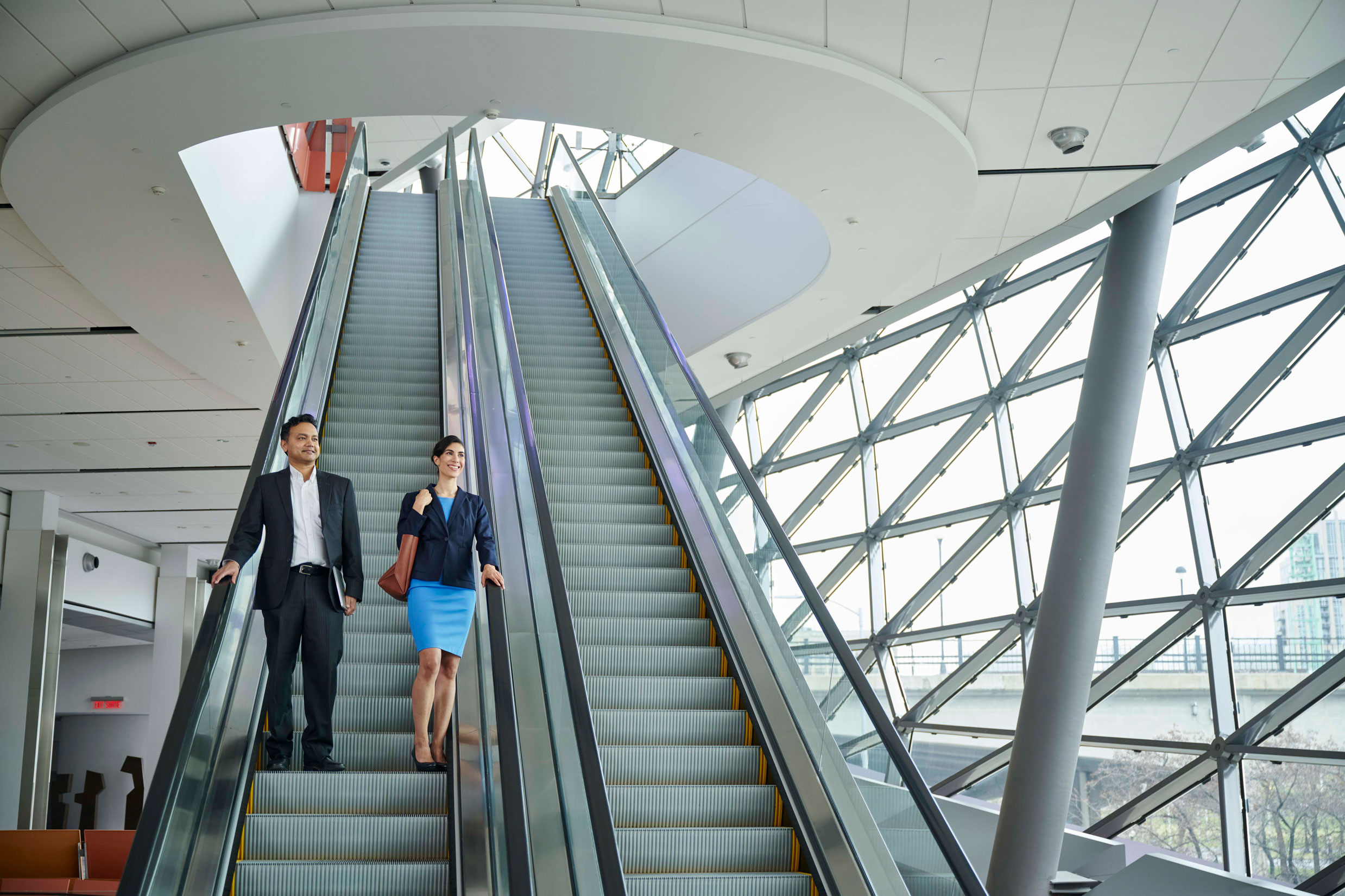 Two professionals coming down an escalator