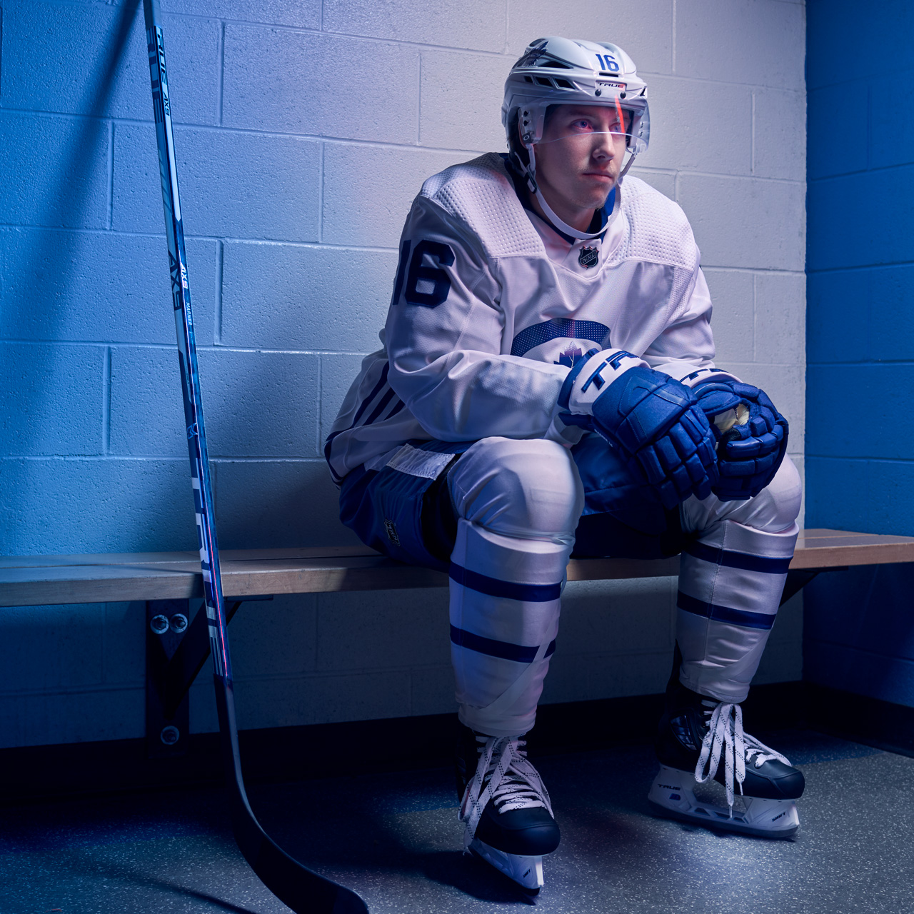 Mitch Marner sitting on a locker room bench in hockey gear