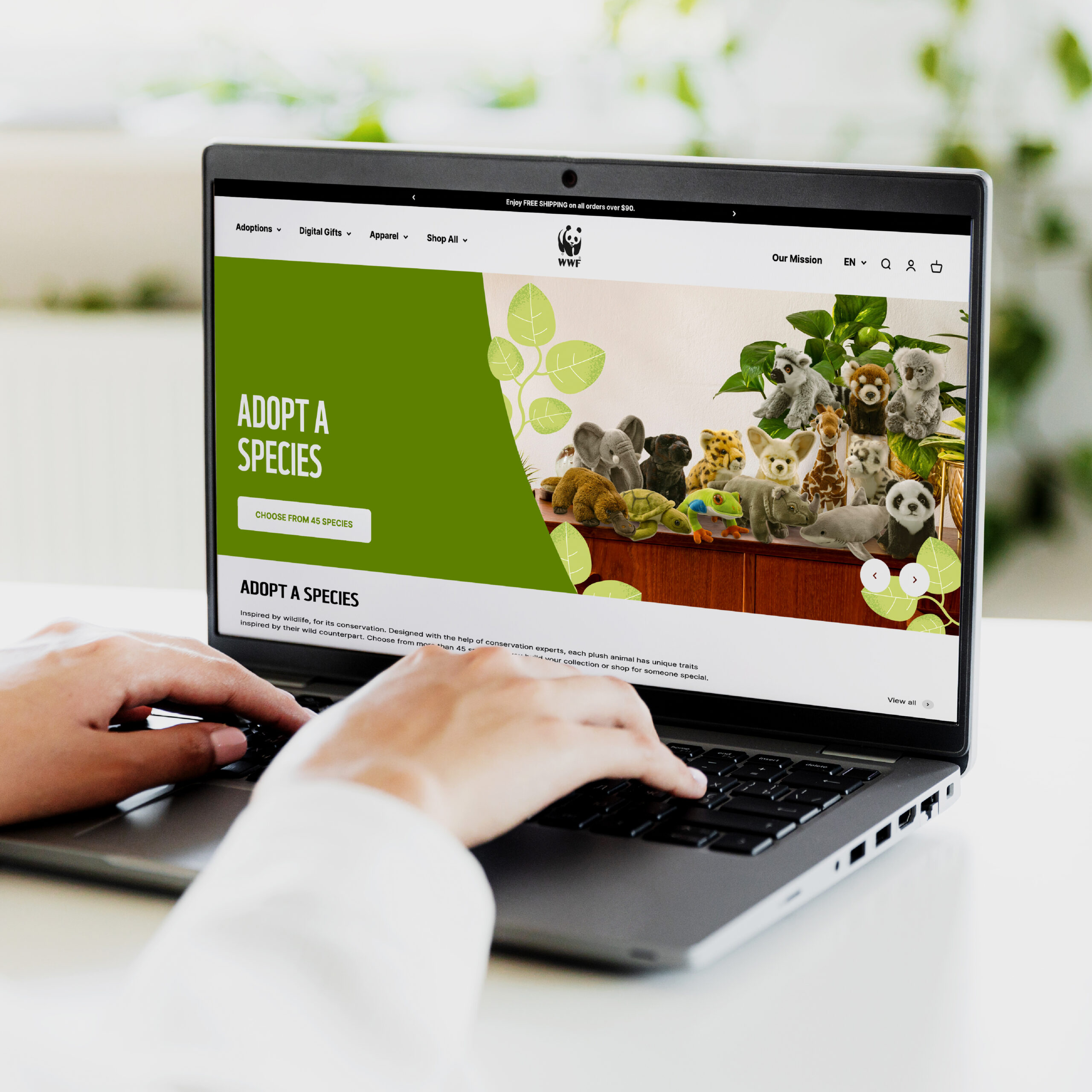 Someone types on a laptop, showing the WWF online shop with a green banner of plush animals.