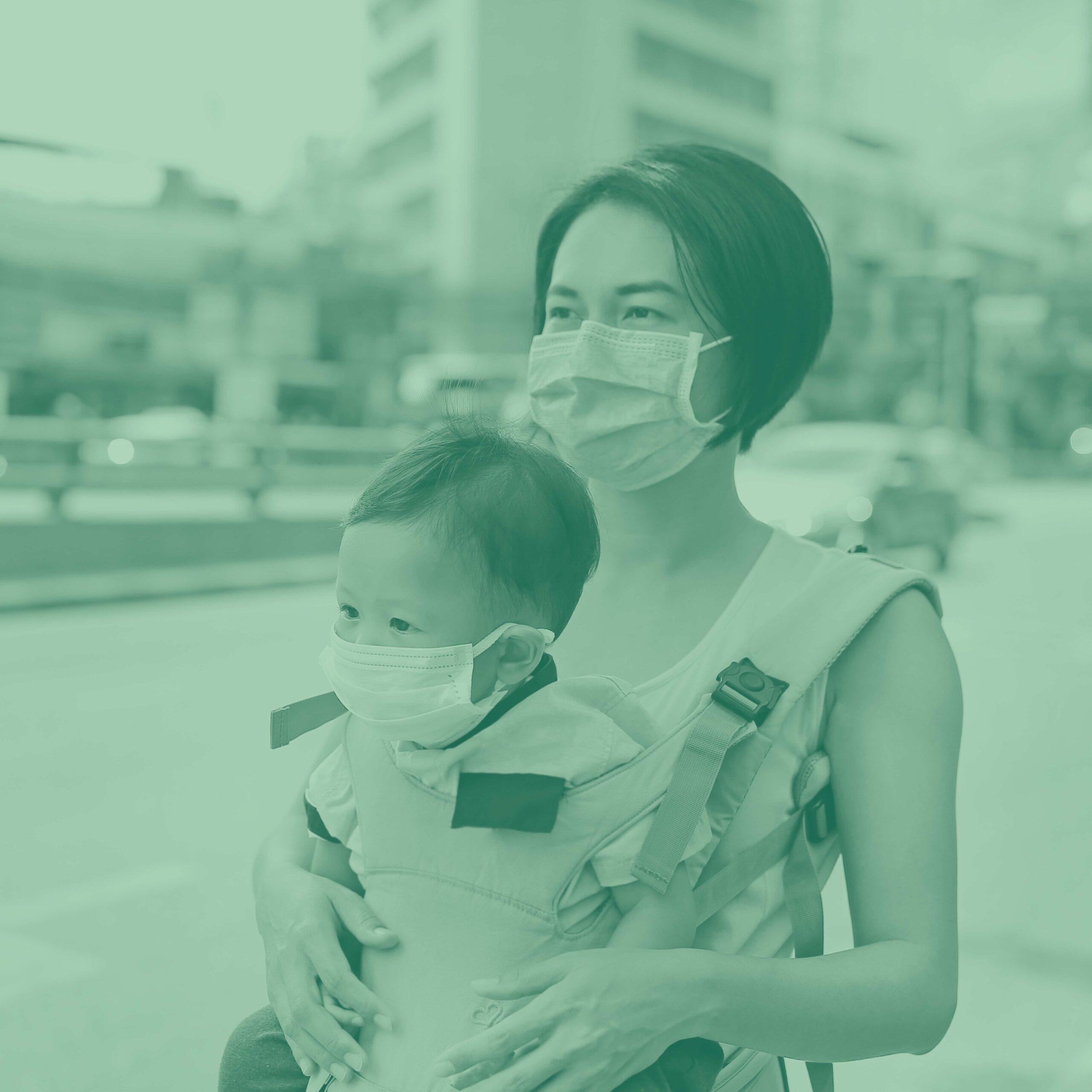 Green tinted image of a person wearing a mask holding a masked baby