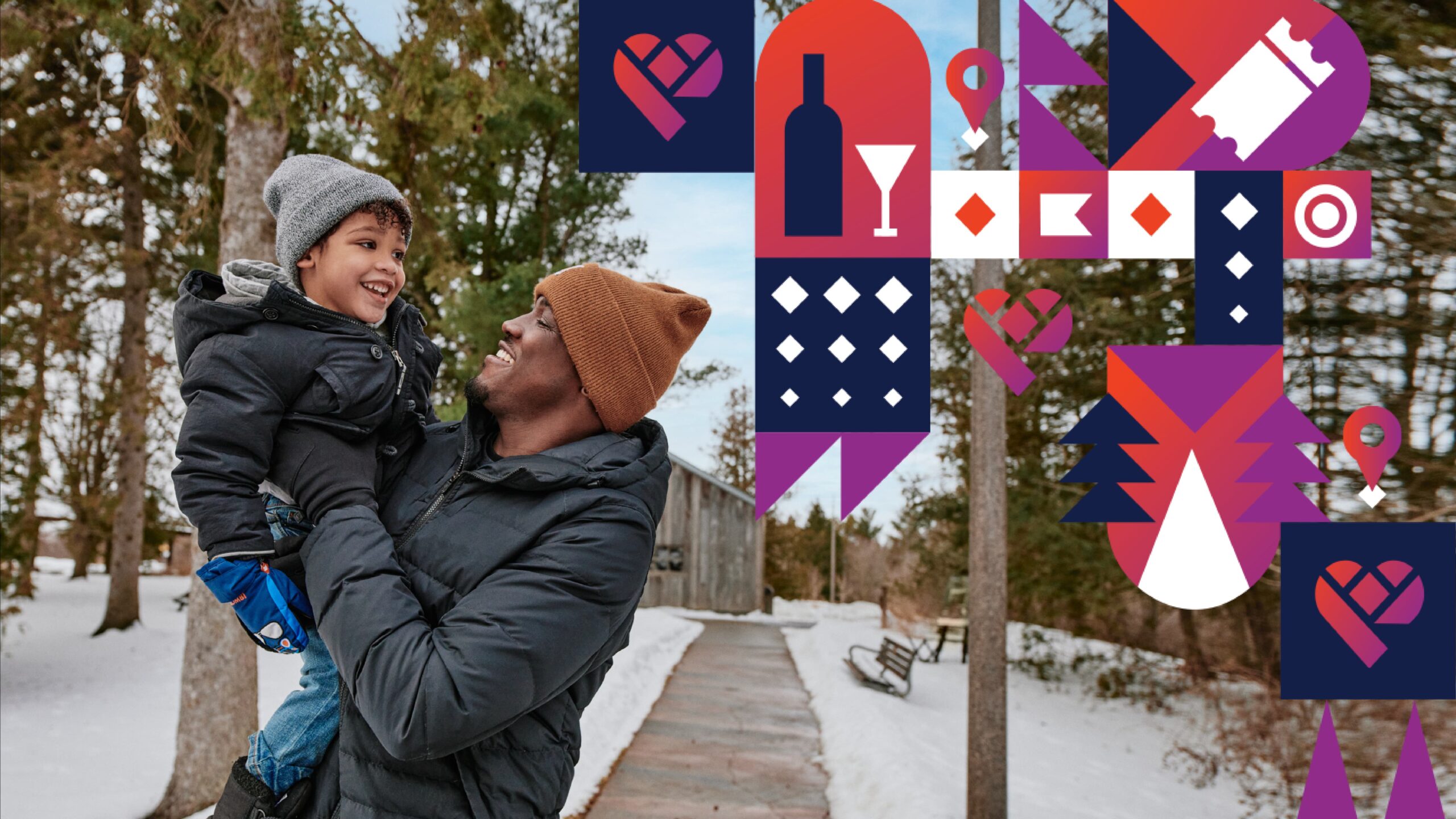Dad carrying and laughing with young son in snow trail.