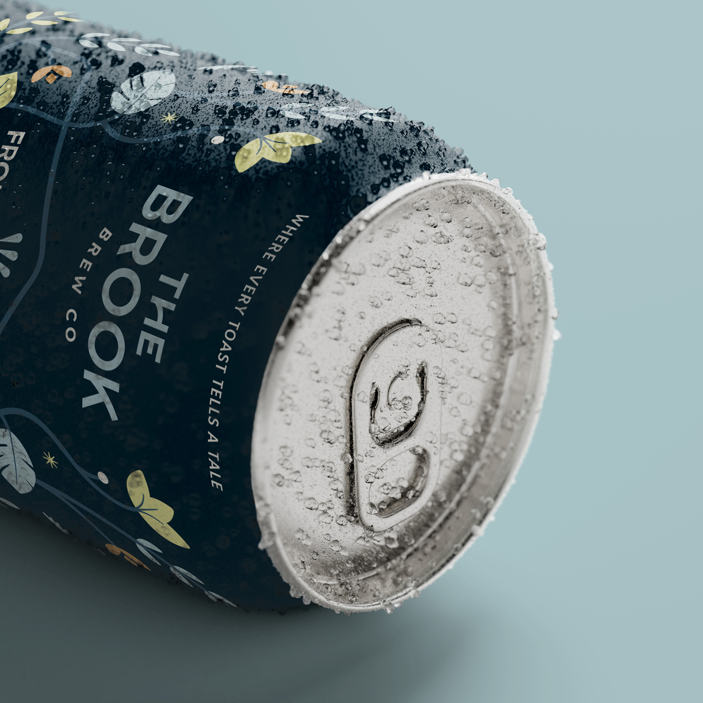 Close-up of a cold, condensation-covered drinks can labelled "The Brook Brew Co" on a light blue surface.