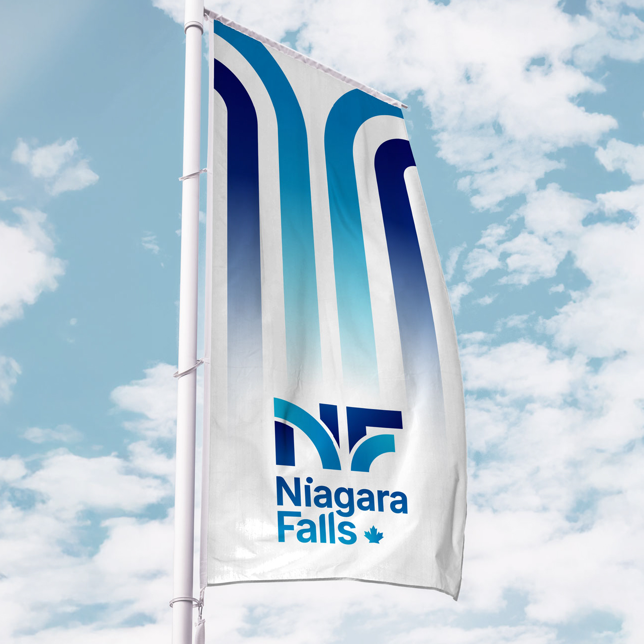 A flag with a blue and white abstract design and the text "Niagara Falls" flying against a partly cloudy sky.